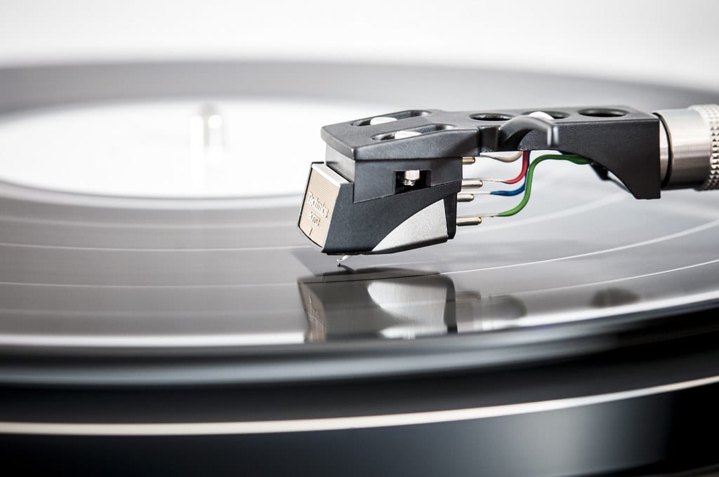 Agulha e cápsula de toca-discos apoiadas sobre um disco de vinil